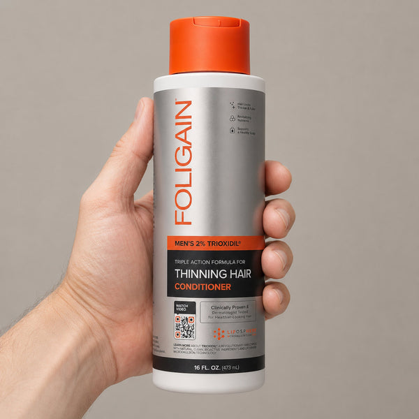 FOLIGAIN Triple Action Conditioner for thinning men's hair with 2% TRIOXIDIL, 473ml bottle, shown in hand.