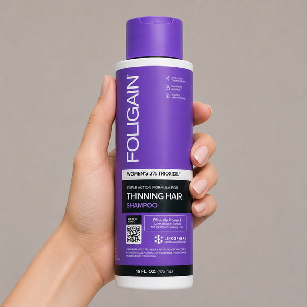 FOLIGAIN Triple Action Shampoo for thinning hair women with 2% TRIOXIDIL in 473ml bottle, showing the shampoo bottle and hand.